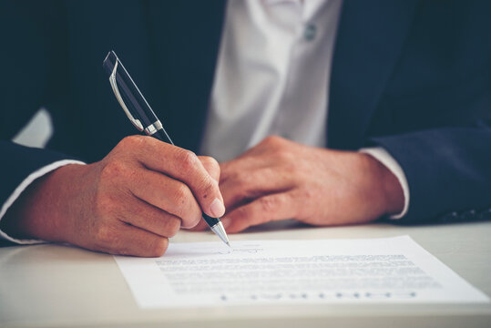 Close up Man hands writing empty notebook planing meeting agenda on wooden table. Close up man hand write using pen note Personal Organizer sign contract. Businessman hands writing pen on paper.
