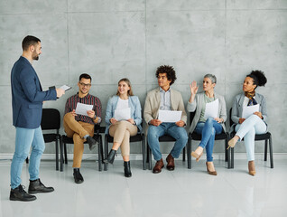 Fototapeta premium Group of young businss people sitting in chairs and waiting for an interview holding application documents