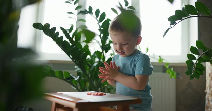 Funny little boy with painted mustache playing with orange modeling clay