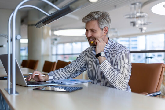 Video call, man with headset and tablet computer looking at camera. Support worker at workplace advising and helping clients remotely.