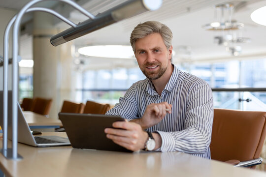 Young modern business man working using digital tablet while sitting in the office