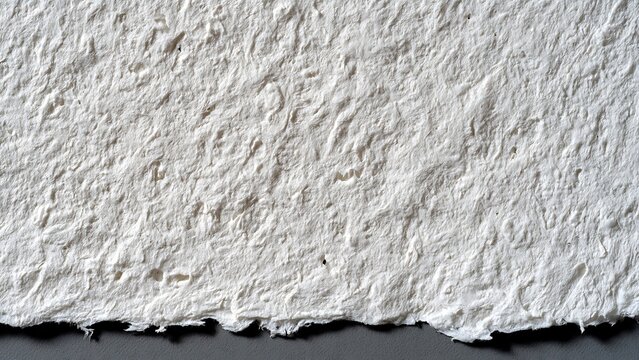 Close up handmade cotton paper showing rich fibrous texture and rough deckled edge