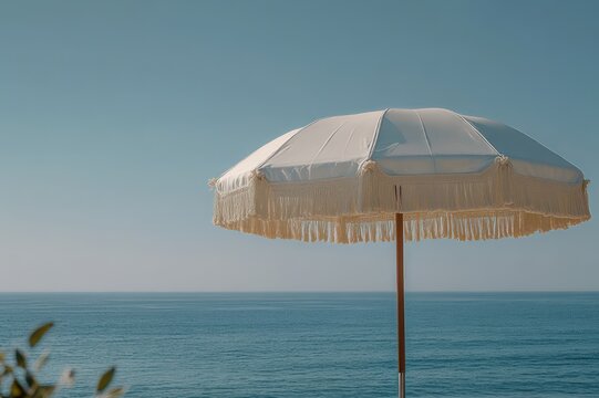 white fringed parasol by calm blue sea under a clear sky conveying peaceful summer relaxation