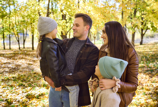 Family parents children smiling together in autumn park. Close portrait of mother and father with two kids, sharing warmth among golden trees. For ads. Concept of loving family relationships.