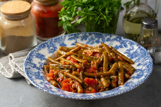 Traditional Turkish green beans stew cooked with tomatoes and olive oil on a ceramic plate