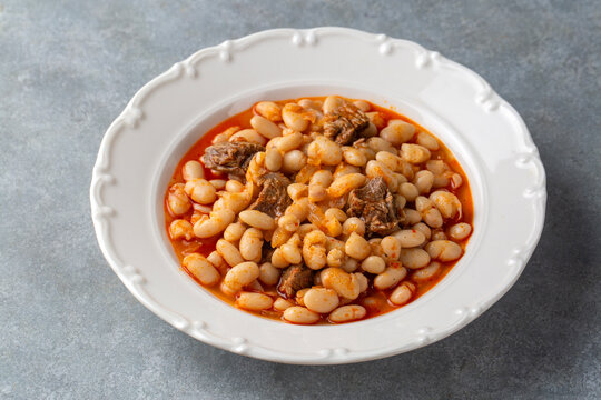 Traditional Turkish etli kuru fasulye white bean stew with meat on a white plate