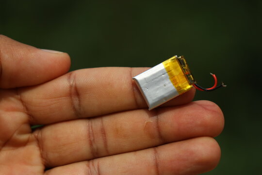 Small li-Po or known as lithium polymer battery with connection wires held in the finger