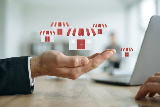 Hand presenting multiple store icons for retail business expansion and franchising