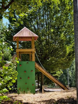 Germany 2026 Wooden playground climber frame with slide tower in lush green park