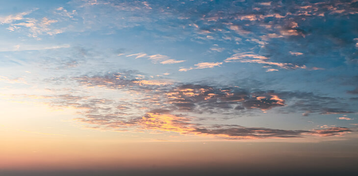 Beautiful sunset sky background with soft pastel orange clouds and clear blue azure light for panoramic travel mockup design