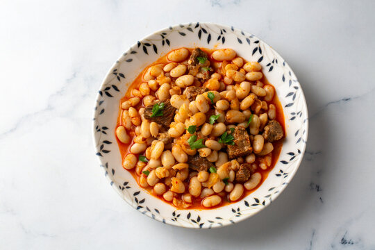Top view of traditional turkish kuru fasulye white bean stew with meat in a ceramic bowl