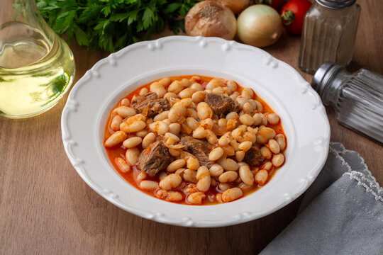Top view of traditional turkish kuru fasulye white bean stew with meat in a ceramic bowl
