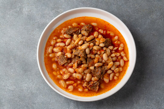 Top view of traditional turkish kuru fasulye white bean stew with meat in a white plate