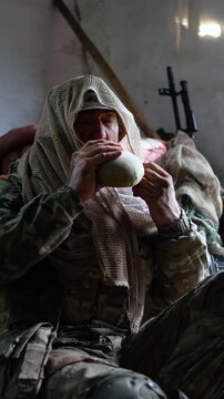 An exhausted, dirty soldier drinks water from a canteen. A brief respite between battles.