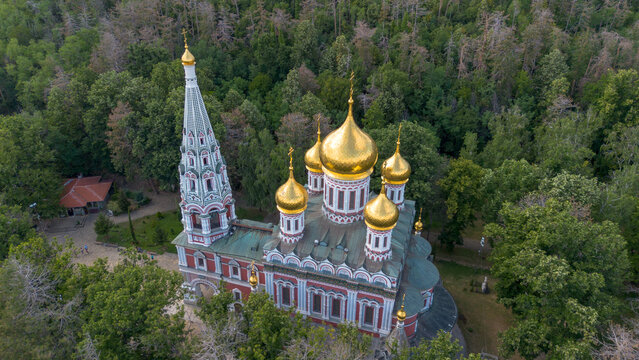 Aerial drone view of the ancient Shipka Memorial Church surrounded by lush green forest in Bulgaria