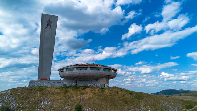 Aerial view of the abandoned communist buzludzha monument on a hill under a blue cloudy sky in Bulgaria