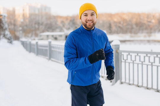 Man running in winter park, enjoying cold weather for a healthy exercise and sport activity