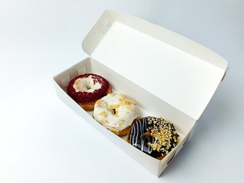 Assorted gourmet donuts in an open takeaway box isolated on a white background, featuring chocolate, almond, and red velvet toppings in a minimalist food presentation
