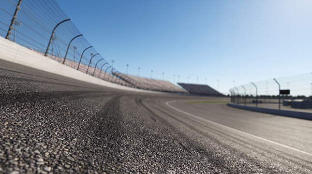 Low-angle close-up of textured asphalt track surface on an empty oval racing circuit