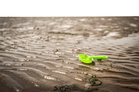 Kids lost plastic spade seen at low tide on a beach which has fast. moving tides and currents and poses a danger to life. The plastic waste adds to marine pollution.