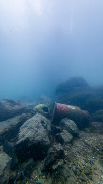 Misty underwater Aare riverbed with abandoned milk churn and debris among rocks - Solothurn, Switzerland