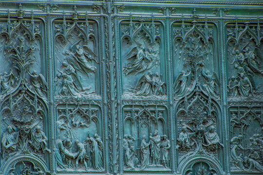 Gothic Bronze Doors with Detailed Relief Sculptures of Angels and Biblical Scenes on the Cathedral in Milan Italy.