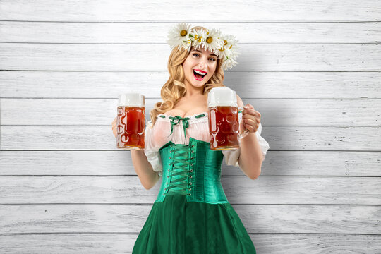 Midsummer woman waitress serving big beer mugs on wooden grey background. Blonde girl with wreath daisies flowers in her hair celebrating traditional beer festival in summer or spring