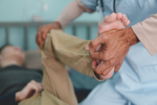 Close-up of a doctor or physical therapist doing leg rehabilitation exercises and medical physical therapy for a male patient at clinic or hospital or nursing home, checking foot mobility.