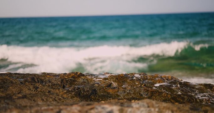Powerful Turquoise Ocean Waves Crash Against Rugged Rocks, Creating Dynamic Sea Foam on a Serene Coastal Shore.
