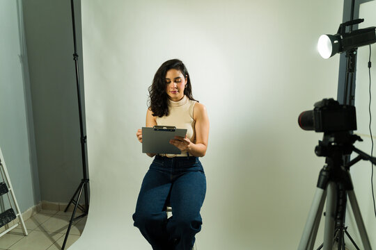 Latin woman preparing for an audition, holding a clipboard in a studio with camera and lighting setup