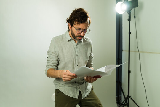 Male talent reading script for a casting audition under studio lights, preparing for his role in a film production
