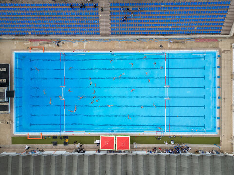 Aerial top down view of a water polo match in an outdoor swimming pool