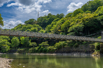 Fototapeta premium Uji Bridge over the Uji River surrounded by lush green forest in Kyoto, Japan