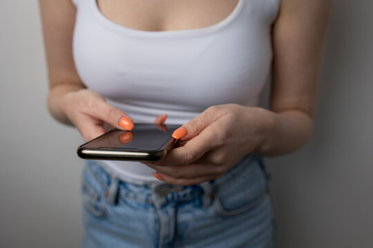 Young Woman Leaning Against Wall While Looking at Smartphone, Concept of Digital Stress and Social Media Anxiety