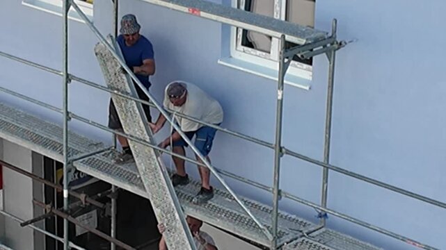 Construction workers on scaffolding installing facade elements on a building