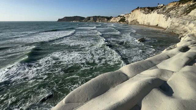Scala dei Turchi. Realmonte, Sicily. Coastal landscape featuring white cliffs and rolling waves under a clear blue sky, showcasing the natural beauty of the shoreline and ocean in a serene environment
