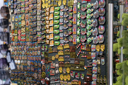Large retail display of colorful Krakow and Poland souvenir fridge magnets in a gift shop, mass-produced travel keepsakes featuring landmarks, symbols and Polish designs
