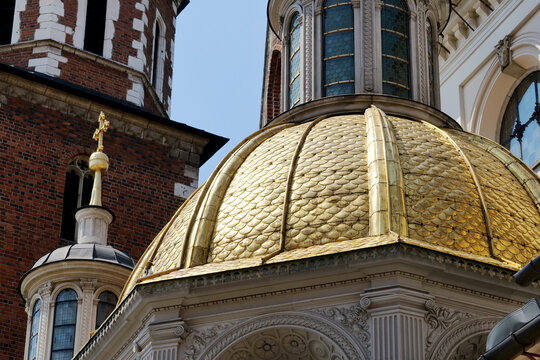 Golden dome of Sigismund Chapel at Wawel Cathedral in Krakow, Poland, close-up low-angle view of Renaissance architecture, ornate stonework, brick tower and blue sky