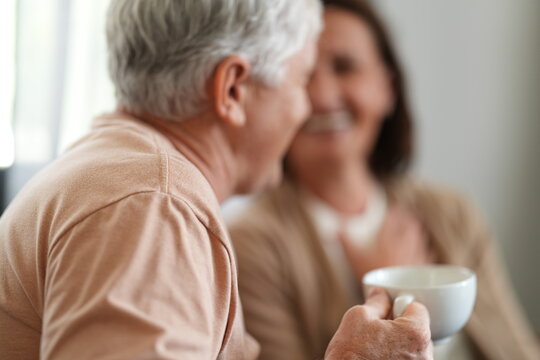 A senior couple enjoy a peaceful morning with coffee in a bright living room, a cosy lifestyle moment of love and belonging, showing the joy of spending time together at home.