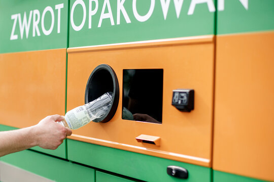 Man hand puts plastic bottle to the Recycling machine. Shoppers return their bottles and cans.kaucja