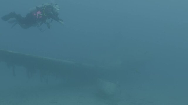 log footage of an airplane wreck underwater scuba divers to explore  metal on ocean floor