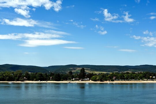 sandy beach on the danube at pilismarot, hungary near the famous visegrad riverbend. tree line on the shore. summer vacation scene. lush green hills background. blue sky. white clouds. travel, tourism