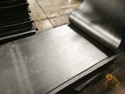 Industrial raw rubber compound sheets stacked in a production plant