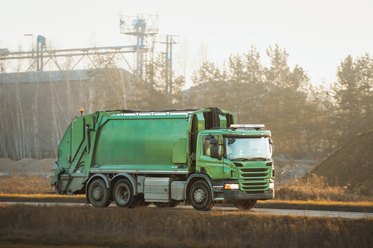 Green garbage truck on early morning route
