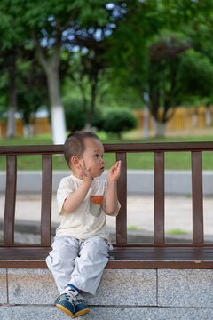Little Asian child standing beside wooden railing