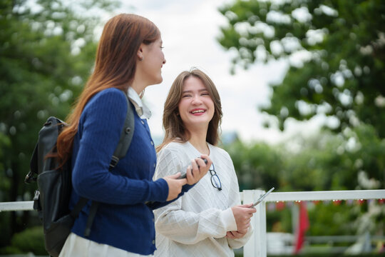 Two Female college students enjoying a friendly conversation while walking across campus in the morning before class.