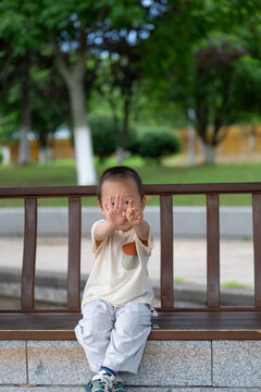 Happy toddler covering face with hands in park