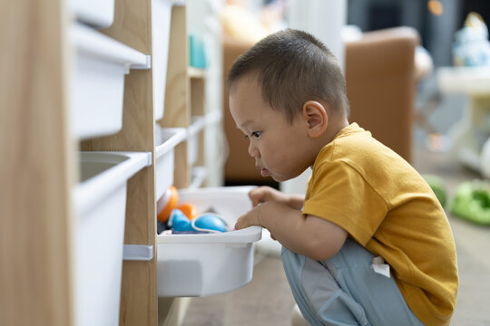 Young Asian child reaching for toys at home