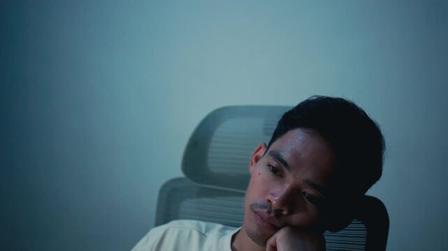 Exhausted young office worker falling asleep in office chair after long working hours