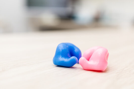 Photo of custom-made two-tone earplugs on a wooden surface.